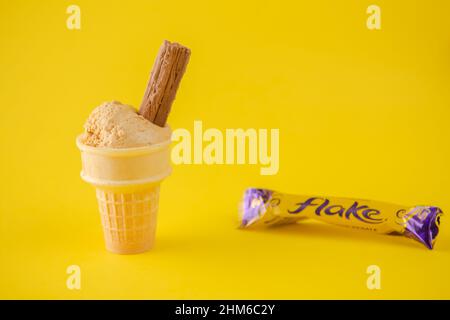 fiocco di cioccolato con gelato al caramello salato fatto in casa in un cono su sfondo giallo con spazio copia Foto Stock