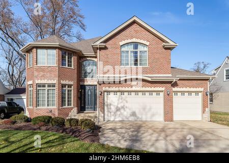 Una grande casa di mattoni rossi a due piani con un garage per tre auto. Foto Stock