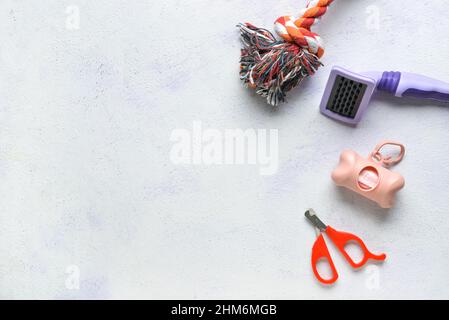 Dispenser con sacchetti per rifiuti e accessori per animali domestici su sfondo chiaro Foto Stock