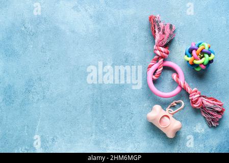 Dispenser con sacchetti per rifiuti animali domestici e giocattoli su sfondo blu Foto Stock