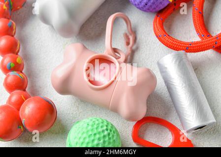 Dispenser con sacchetti per rifiuti animali domestici e accessori su sfondo chiaro, primo piano Foto Stock