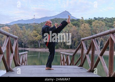 uomo che pratica la disciplina di sipagkido all'aperto in un lago in un sunn Foto Stock