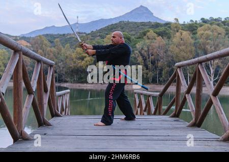 uomo che pratica la disciplina di sipagkido all'aperto in un lago in un sunn Foto Stock