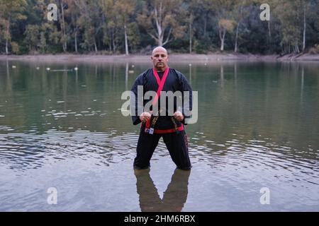 uomo che pratica la disciplina di sipagkido all'aperto in un lago in un sunn Foto Stock