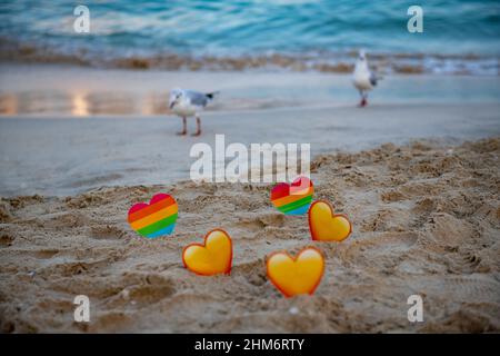 uccelli e lgbt e cuori gialli nella sabbia stand Foto Stock