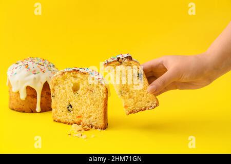 Donna che tiene un pezzo di dolce pasquale delizioso su sfondo giallo Foto Stock