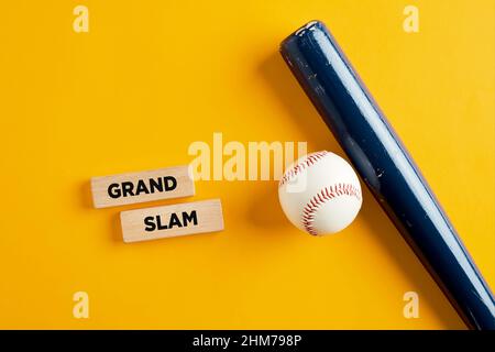 Palla da baseball e pipistrello di legno su sfondo giallo con le parole Grand slam su blocchi di legno. Home run hit nel baseball. Foto Stock