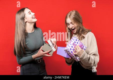 Adorabili ragazze scambio scatole regalo. Due simpatiche amiche si regalano a vicenda. Regali per l'anno nuovo. Natale. Sorelle. Amici. Compleanno. Foto Stock