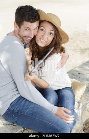coppia giocosa sulla spiaggia che abbraccia e fa volti divertenti Foto Stock
