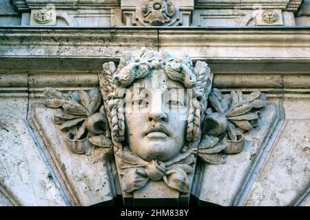 Primo piano di un volto umano in pietra come decor o mascaron sulla facciata dell'edificio Foto Stock
