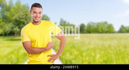 Giovane uomo latino che mostra puntando marketing all'aperto parco annuncio pubblicitario persone banner copyspace spazio all'esterno Foto Stock