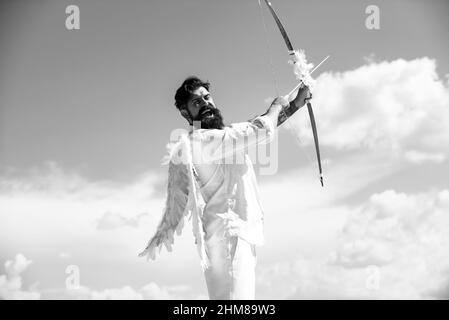 San Valentino concetto. Divertente angelo Cupido puntando con arco e freccia su uno sfondo cielo in cielo. Concetto comico dell'umorismo. Foto Stock