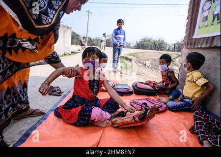 Nabin Nagar, Bengala Occidentale, India. 7th Feb 2022. Il governo dello Stato del Bengala occidentale ha lanciato "'˜Paray Shikshalaya' a decorrere dal 7th febbraio, Uno sforzo di scolarizzazione basato sulla comunità nei quartieri che mira gli studenti primari a mirare al programma è quello di svezzare una grande sezione di studenti che ha abbandonato il sistema di istruzione formale negli ultimi due anni a causa della chiusura delle scuole, a causa di Covid-19. Una classe preprimaria della scuola elementare di confine India-Bangladesh è stata portata su una strada vuota accanto alla recinzione a Nabin Nagar, ci sono occasionalmente animali domestici che entrano. (Credito Foto Stock