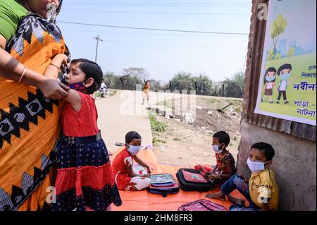 Nabin Nagar, Bengala Occidentale, India. 7th Feb 2022. Il governo dello Stato del Bengala occidentale ha lanciato "'˜Paray Shikshalaya' a decorrere dal 7th febbraio, Uno sforzo di scolarizzazione basato sulla comunità nei quartieri che mira gli studenti primari a mirare al programma è quello di svezzare una grande sezione di studenti che ha abbandonato il sistema di istruzione formale negli ultimi due anni a causa della chiusura delle scuole, a causa di Covid-19. Una classe preprimaria della scuola elementare di confine India-Bangladesh è stata portata su una strada vuota accanto alla recinzione a Nabin Nagar, ci sono occasionalmente animali domestici che entrano. (Credito Foto Stock