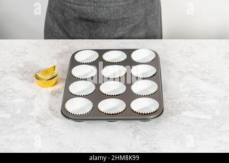 Foderare la teglia per cupcake con i fodere per preparare i cupcake di s'mers. Foto Stock
