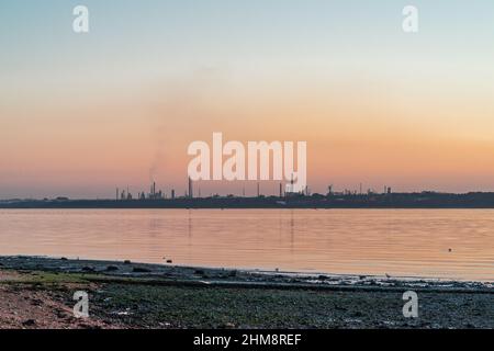 Raffineria di olio di Fawley durante il tramonto come visto da Weston Shore, Southampton, Hampshire, Inghilterra, Regno Unito Foto Stock