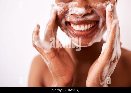 Mi lavo il viso due volte al giorno. Studio girato di una donna irriconoscibile lavando il suo viso su uno sfondo bianco. Foto Stock