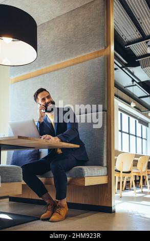 Giovane uomo d'affari che parla per telefono. Felice uomo d'affari giovane sorridente mentre comunica con i suoi soci di affari. Imprenditore di successo WO Foto Stock