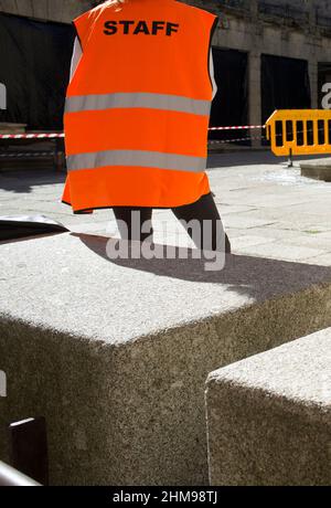 Il lavoratore del personale guarda l'area di sicurezza contrassegnata da recinzione mobile e coni e nastro Foto Stock