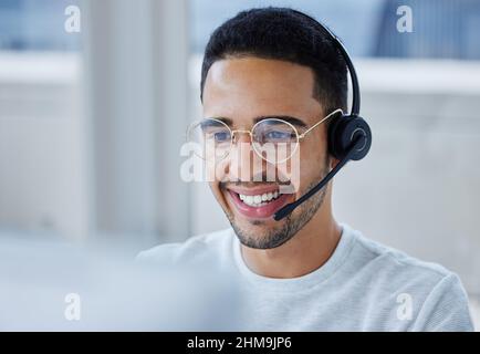 Questo cliente sembra particolarmente soddisfatto del mio lavoro. Scatto di un giovane uomo d'affari che lavora alla sua scrivania nel suo ufficio. Foto Stock