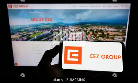 Persona che tiene uno smartphone con il logo dell'azienda energetica ceca CEZ a.s. sullo schermo di fronte al sito Web. Mettere a fuoco sul display del telefono. Foto Stock