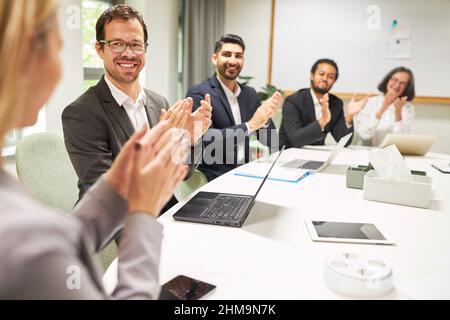 Gruppo di uomini d'affari che danno applausi e applaudire per approvazione e lode in ufficio Foto Stock