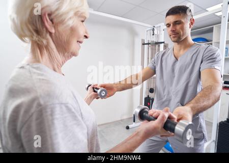 Fisioterapista che aiuta le donne pensionati a sollevare manubri Foto Stock