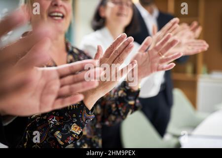 Gruppo di uomini d'affari che si applaude e applaude con le mani in ufficio Foto Stock