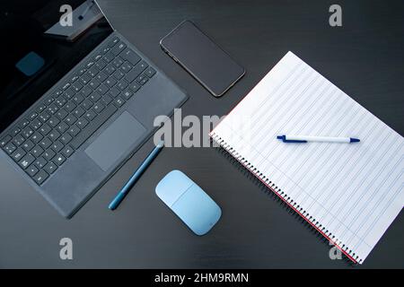 Immagine di un tablet e un blocco note per notebook con una penna su un tavolo nero pronto per studiare o lavorare da casa Foto Stock