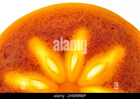 Primo piano di un pezzo di persimmon fresco maturo, mezza fetta rotonda su uno sfondo bianco isolato.luce luminosa nel mezzo del frutto. Foto di alta qualità Foto Stock