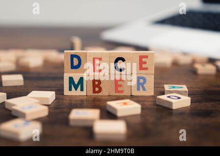 Il nome del mese di dicembre scritto su cubi di legno del tavolo del computer scrivania. Foto di alta qualità Foto Stock