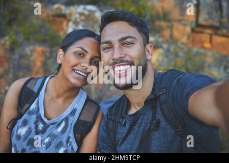 Voglio ricordarlo per sempre. Scatto di una giovane coppia che scatta foto mentre si è fuori in un'escursione in una catena montuosa all'aperto. Foto Stock