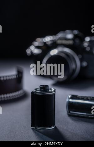 Fotografia di film - una cartuccia di film metallico vintage e una fotocamera reflex 35mm su sfondo scuro. Foto Stock