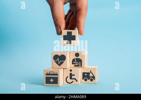 Disposizione manuale del blocco di legno impilamento con l'icona medico sanitario. Assicurazione sanitaria - concetto di salute Foto Stock