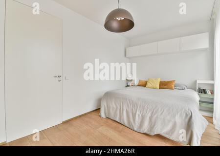Comodo letto con coperta e cuscini in una camera da letto elegante e luminosa Foto Stock