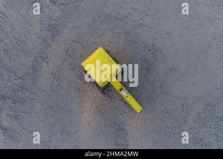 Spettacolare vista aerea dall'alto della torre del bagnino giallo luminoso situata sulla spiaggia sabbiosa di fronte al mare blu sotto il cielo solato Foto Stock