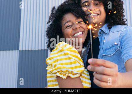 Gioiosa coppia ispanica con ricci afro abbracciando teneramente e scintillio ardente per un'occasione speciale di festa Foto Stock