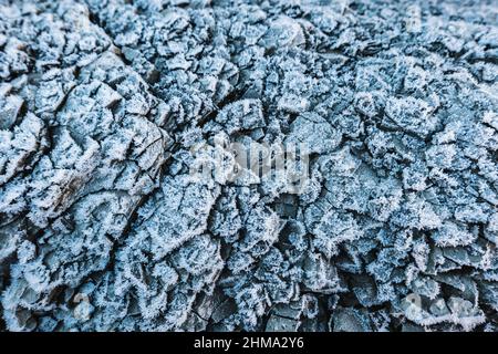 Sfondo astratto full frame di struttura rocciosa crackizzata con gelo su superficie ruvida Foto Stock