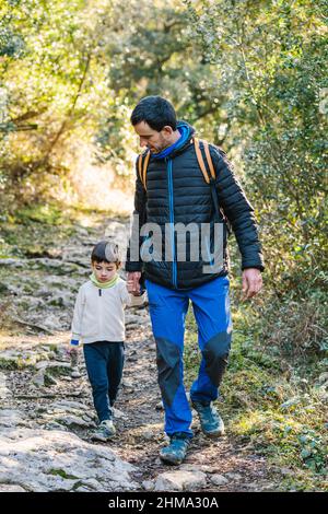 uomo e ragazzino che maneggiano e camminano lungo sentieri rocciosi mentre si cammina nei boschi autunnali Foto Stock