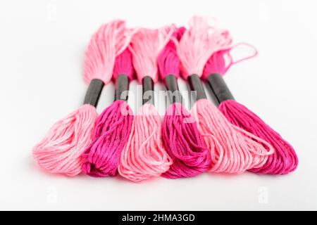 Cinque fili da cucito rosa vivido per ricami isolati su un tavolo bianco, vista dall'alto o posa piatta di materiali tessili Foto Stock