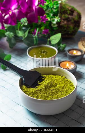 Da sopra composizione con ciotola di henné in polvere morto vicino spazzola pettine di legno e candele brucianti per la cura naturale dei capelli Foto Stock