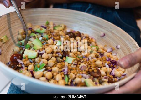 Coltivare giovane femmina afroamericana mangiare gustosa insalata di verdure in cucina a casa Foto Stock