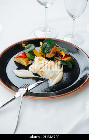 Fettine di filetto di pesce leggermente fritte splendidamente placcate con metà di mais Foto Stock