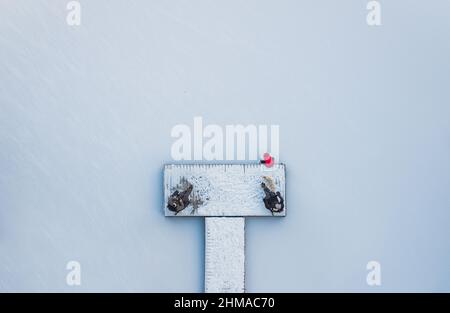 Vista aerea di persone sedute sul molo nevoso sul lago ghiacciato in inverno. Foto Stock