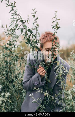 Donna russa rossa che gioca in foglie d'albero il giorno d'autunno Foto Stock