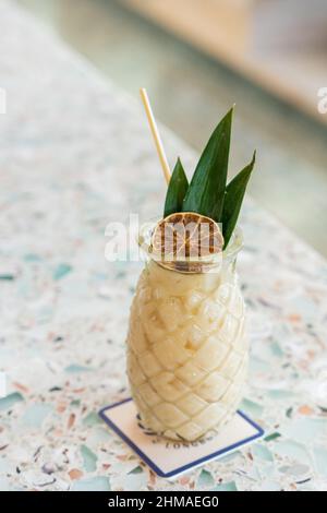 Cocktail al rum con ananas al cocco fruttato su un bar in vetro riciclato Foto Stock