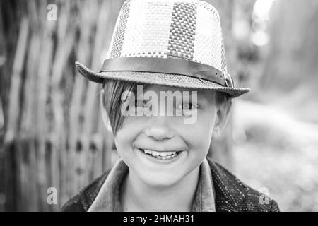 Ragazzo sorridente che gioca con le foglie e guarda la macchina fotografica. Primo piano verticale. Ragazzo carino. Foto Stock