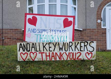 Un casalingo ha messo i segni fatti in casa nel loro giardino anteriore. I segni rendono omaggio e un ringraziamento all'NHS, al suo personale e a tutti i principali lavoratori Foto Stock