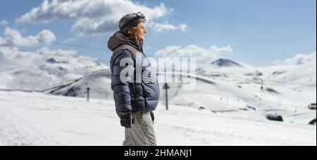 Uomo maturo in giacca invernale e pantaloni che camminano su una montagna innevata Foto Stock