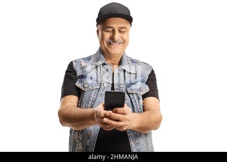 Uomo maturo sorridente in un gilet in denim utilizzando uno smartphone e digitando isolato su sfondo bianco Foto Stock